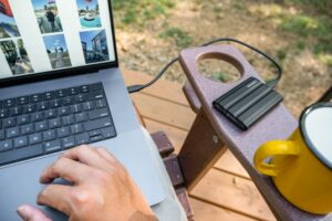 Person using laptop with external hard drive and mug researching sba business loan 