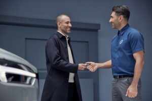 car salesman finalizing deal and handing keys to customer after expanding business with private loans for business