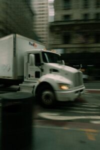 A white fedex truck driving on a city street
